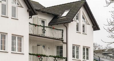 modern two-story house with a wooden porch and large windows, showcasing a tidy exterior